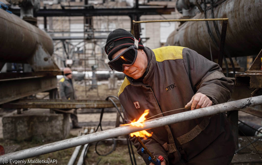 Man wearing goggles welding pipe (© Evgeniy Maloletka/AP)
